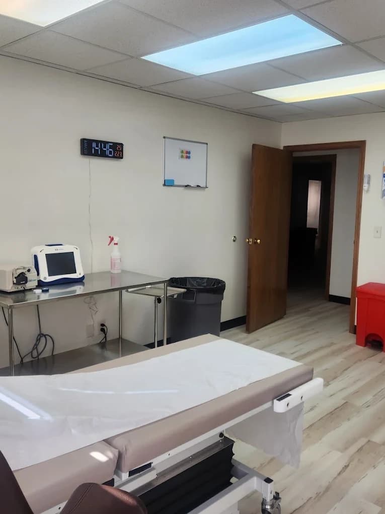A prepared Vein-ity treatment room with fresh paper on the examination table, a monitor on a stand and a digital clock on the wall.